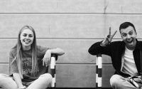 Happy young adults sitting together, embracing fun and friendship in a grayscale photo.